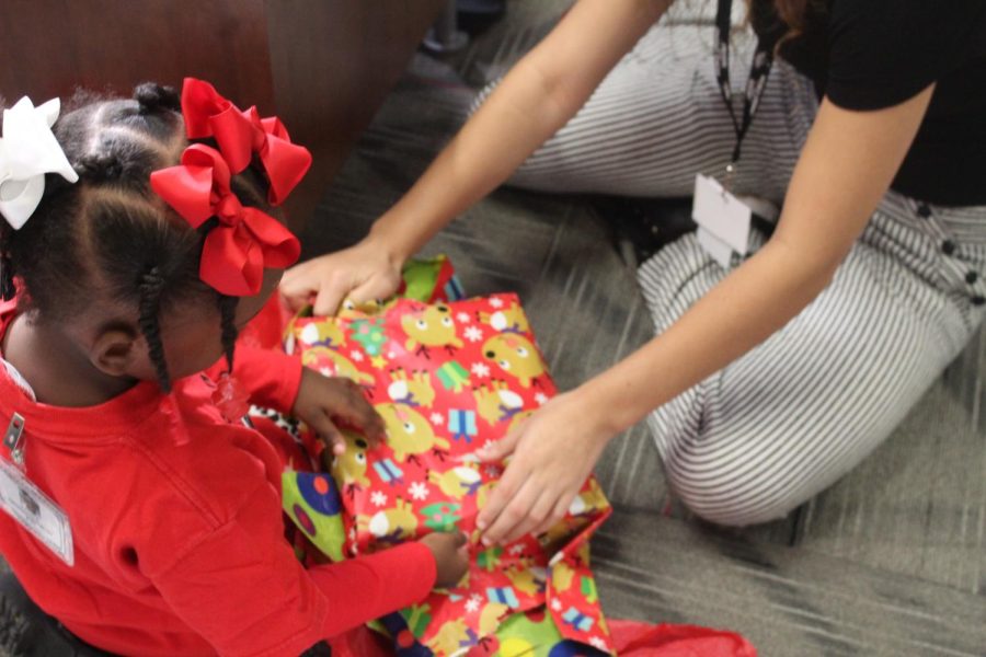 One child opens her presents while a few volunteers help as the rest of the class watches her from outside one of the Bengal boxes. 