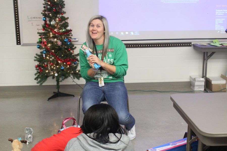 The class gathers around to watch Coach Weise play with their project adoption child. 