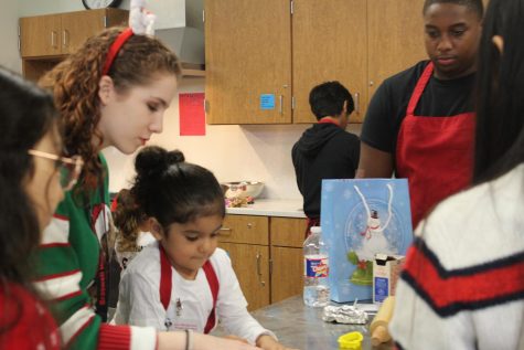 The culinary class helps two children bake cookies. Everyone helps in different ways and the children leave with cookies and an entertaining story to their parents. 