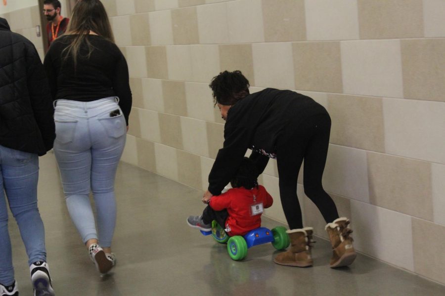 Being close to the end of the period, a class that gave children electrical cars and bicycles takes one student out for a zip up and down the hallways.